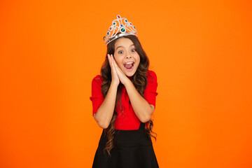 Teen girl in crown at birthday party. Party celebration. Girlish princess crown. Happy teen girl in princess crown. Party princess. Happy birthday. Birthday girl isolated on orange. Birthday surprise