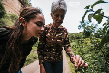 Naklejka premium Mother and daughter exploring in the forest, observing plants