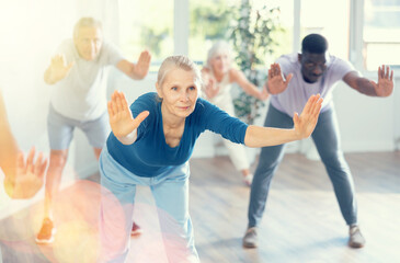Obraz premium Active mature men and women practicing Rock 'n' Roll dance in training hall during dancing classes