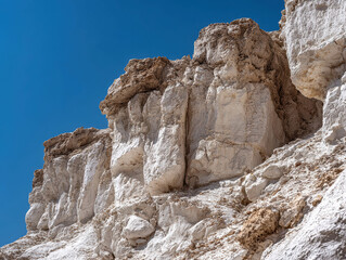 Fototapeta premium A midday photograph captures a barren, mountainous canyon landscape with steep rock formations in various shades of brown and gray The clear blue sky suggests fair weather conditions - AI-Generated