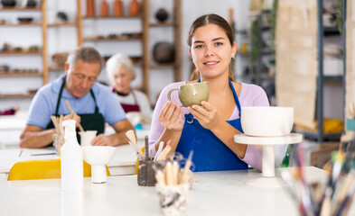 Young female potter student demonstrates pottery made by her own hands