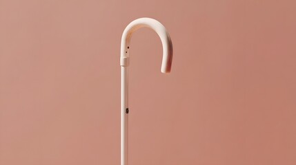 A light beige umbrella handle curves elegantly against a muted peach backdrop.