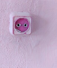 Rustic pink wall with worn electric socket in pastel interior design