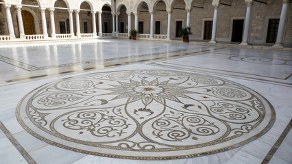 Obraz premium Interior courtyard with marble floor and columns featuring a large circular mosaic design center