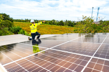 A confident engineer smiles and points at the camera while working on a rooftop solar panel...