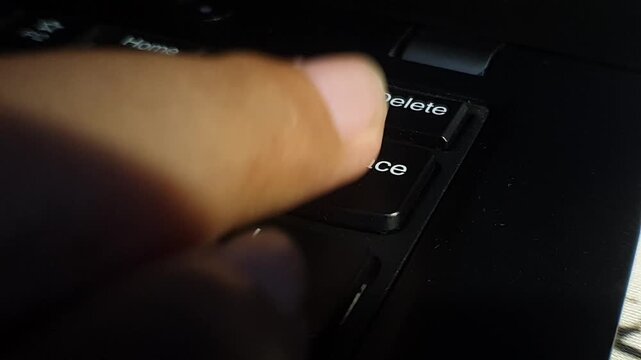 Close-up of a finger pressing the 'Backspace' key on a laptop keyboard. Shows correction, editing, or data entry, highlighting digital work and human-computer interaction.