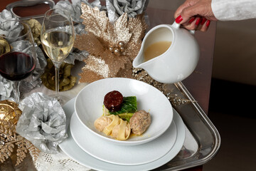 Elegant Escudella Soup Being Poured on Silver Platter with Red Wine and Champagne – Refined Christmas Dining Scene