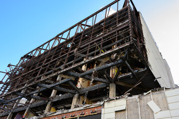 Ruined abandoned building with exposed metal framework and crumbling concrete walls after demolition or destruction, industrial ruins and damaged architecture under blue sky