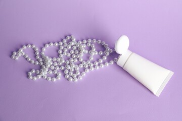 Cream with pearl necklace on lilac background