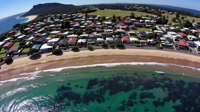 Panoramic seaside outlook across beach and marine promenade in town towards prominent headland cape