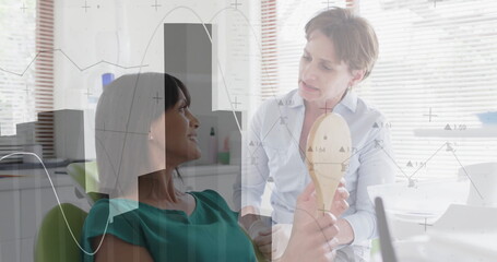 Holding mirror, woman patient comparing shade guide with clinician in dental chair, copy space