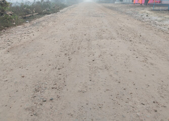Initial stage of rural road construction with freshly laid concrete layer and water sprinkling for surface settling, part of multi-layer road building process in India
