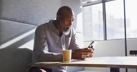 Businessman lifting smartphone, scrolling as code lines sweep across him, gazing skyline reflecting - Powered by Adobe
