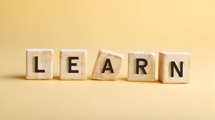 Learning Concept with Wooden Alphabet Cubes and Yellow Pastel Backdrop