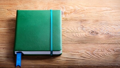 Fototapeta premium green notebook with blue bookmark on wooden surface