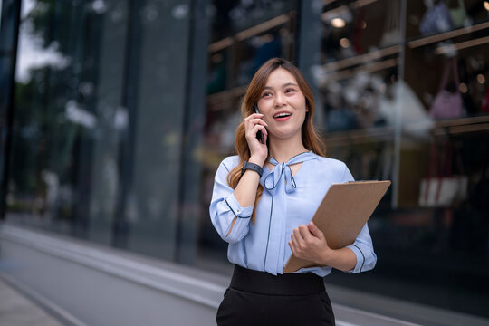 woman is talking on her cell phone while holding a clipboard