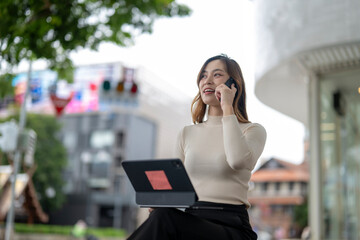 Fototapeta premium woman is talking on her cell phone while sitting on a bench