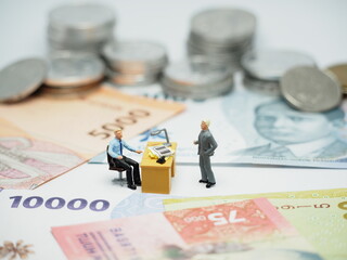 Mini toy of action figure at table with blurred background. Toy photography concept design. Minifigure of boss character with his employee on pay day.