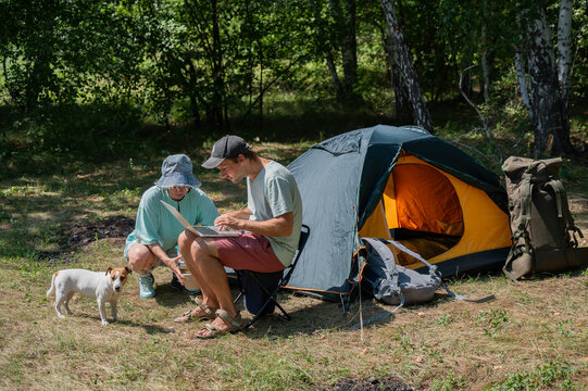 Caucasian man working on laptop in camping. Couple relaxing in nature.