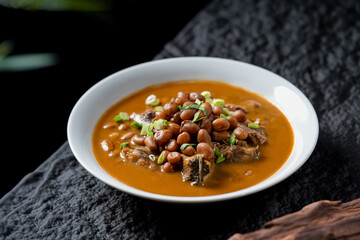 A bowl of delicious stew featuring peanuts and meat pieces in a savory sauce, presented attractively.