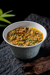 A bowl of minced meat soup with vibrant garnish, showcasing a savory and appetizing dish.