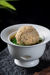A steamed meatball served in soup with green vegetables, presenting a delicious and appetizing appearance.