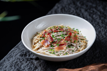 A plate of stir - fried shredded taro with bacon and green onions, showing a delicious and appetizing appearance.