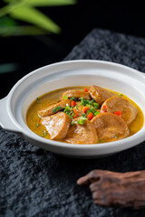 A bowl of braised pork slices in rich gravy, garnished with colorful toppings, presenting a sumptuous and appetizing food dish.