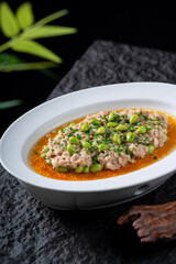A plate of steamed minced pork with edamame, presented in a white bowl, showcasing a delicious and appetizing dish.