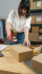 Woman Sealing Kraft Mailer with Tape Gun in Tidy Studio