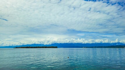 Scenic view of Mansinam Island in Manokwari, West Papua, with calm blue ocean, tropical coastline, and dramatic cloudy sky.