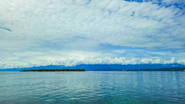Scenic view of Mansinam Island in Manokwari, West Papua, with calm blue ocean, tropical coastline, and dramatic cloudy sky.