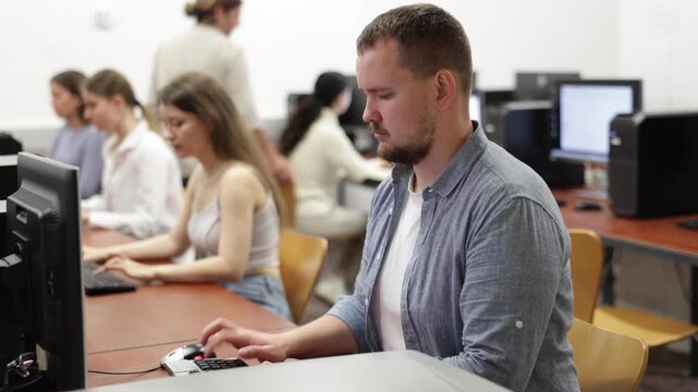 Man student of computer courses types on keyboard, performs work, educational practical task. Pupil performs educational tasks using computer