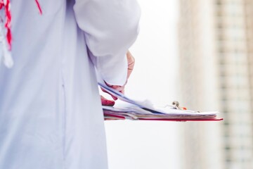 Portrait Islamic man smile working outdoor holding file folder using smartphone digital tablet muslim dress in modern uae city. Saudi Arab men wear hijab Headscarf muslim formal dress lifestyle