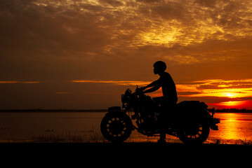Silhouette Motorcycle sunset golden sky background. Motorbike park in nature garden outdoors country lake view sunrise water reflection sunbeam at dawn. Silhouette Motorcycle biking golden landscape