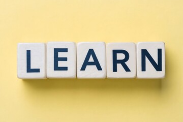 Obraz premium White blocks spelling LEARN in dark blue letters on a yellow background learn learning