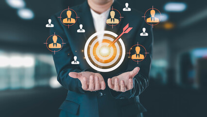 A businessman in a suit holds a glowing target with an arrow in the bullseye, symbolizing customer targeting, marketing strategy, and achieving business goals.