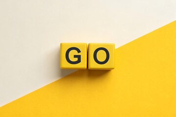 Word GO spelled out with yellow letter blocks on a split yellow and cream background start begin