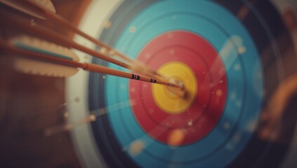 Detailed close up of wooden arrows striking the bullseye upon the colorful archery target, captured within sharp focus featuring blurred background and warm natural lighting