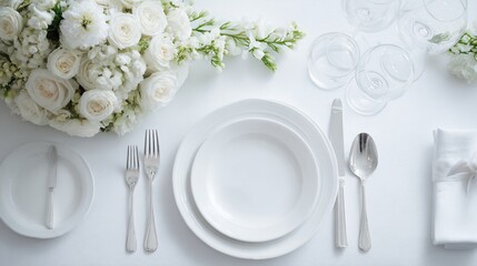 Elegant white table setting with flowers, flatware, and glassware