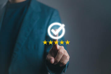 Businessman pointing at digital check mark with five star rating, representing quality assurance,...