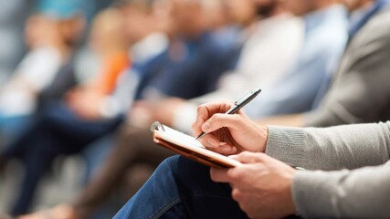Person Writing in Notebook at Event
