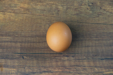 Light brown shelled chicken eggs lay on a wooden floor.
