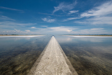 Vast flooded runway extends across plain, mirroring blue sky, evoking tranquility