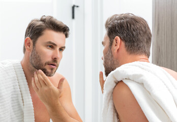 Fototapeta premium Beauty face portrait of a beautiful man applying face cream. Skincare cream for man. Mask, skin lifting and anti-aging effect. Beauty male face concept. Skincare and aging. Face cosmetic.