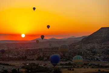 Hot air balloon flying over rocky landscape at sunrise in Cappadocia. Turkey