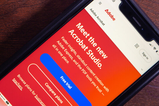 Mexico City, MEXICO - Aug 26 2025 : Close-up of a smartphone displaying the Adobe Acrobat Studio introduction page with content creation tools, trial offer, and plans.