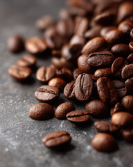 Naklejka premium Dark roasted coffee beans scattered on stone surface create an inviting aroma