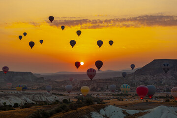Hot air balloon flying over rocky landscape at sunrise in Cappadocia. Turkey