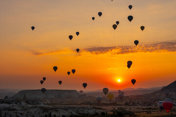 Hot air balloon flying over rocky landscape at sunrise in Cappadocia. Turkey
